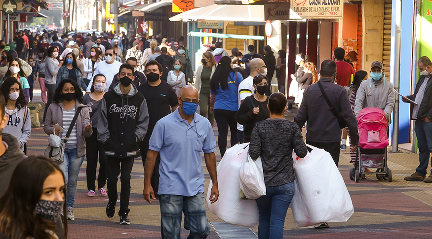 #PraCegoVer Pessoas de máscaras andando na rua