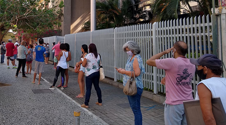 #PraTodosVerem Várias pessoas em fila, perto de uma cerca.